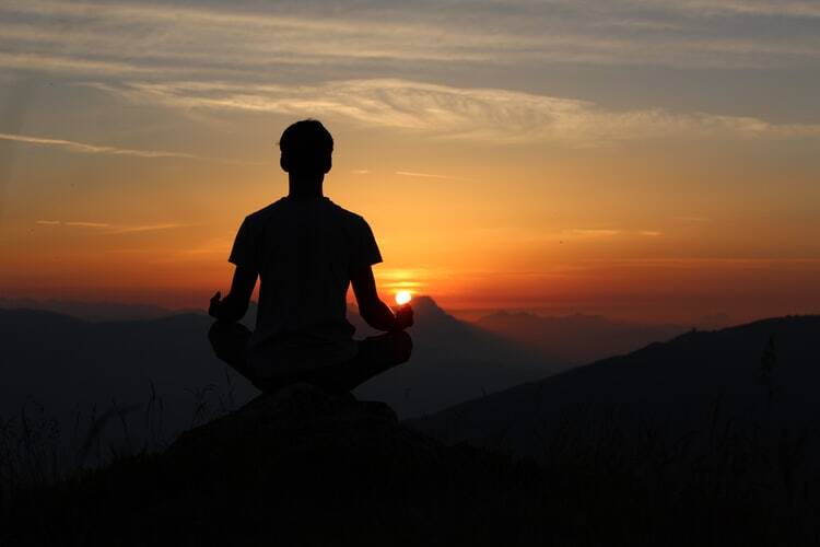 A man meditating on the peak of a mountain