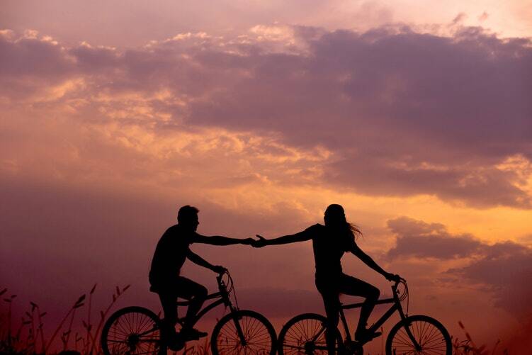 A couple in a relationship riding bikes in the sunset