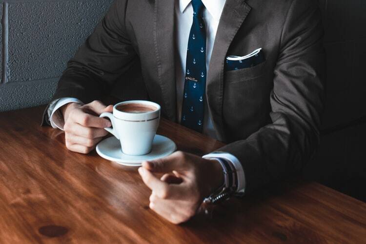 A high-value man with a suit drinking coffee